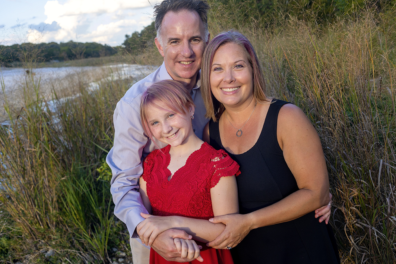family of three posing by the San Gabriel River