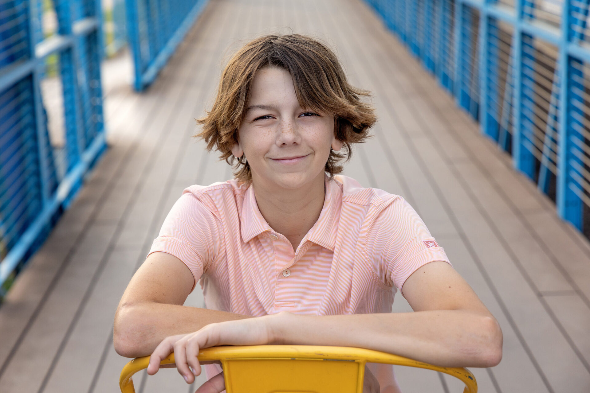 child sitting in yellow chair on blue wooden bridge