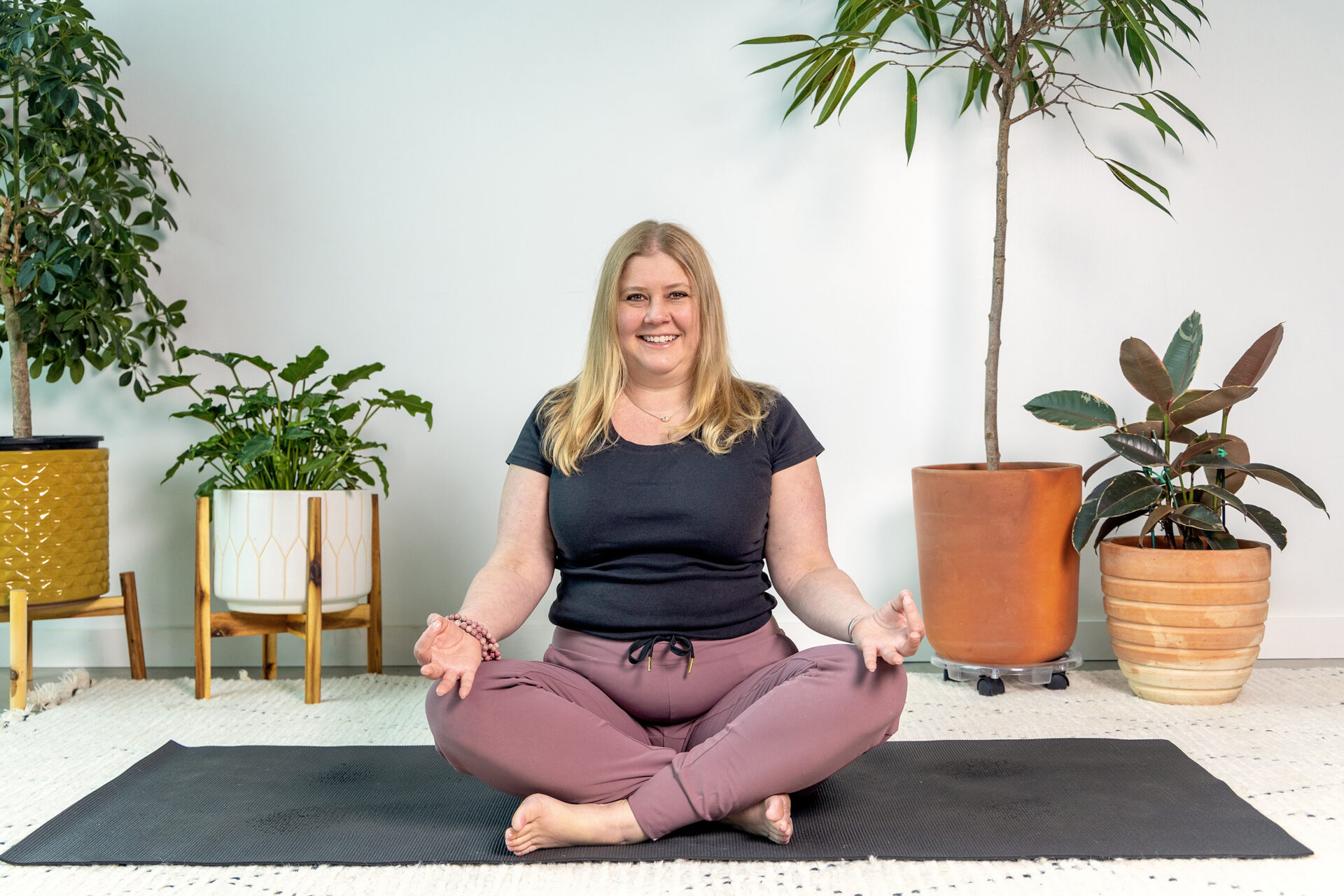 yoga teacher demonstrating a pose on a black yoga mat in a studio