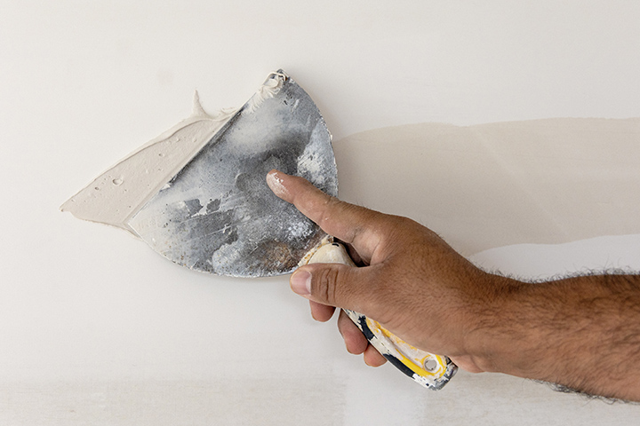 close-up of hand putting drywall on a house wall