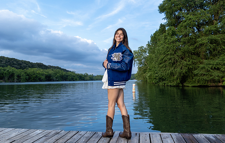 Senior in her letter jacket on a dock for a photo session in Austin, Texas