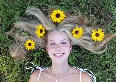 girl with sunflowers in her hair for senior photo session at commons ford ranch