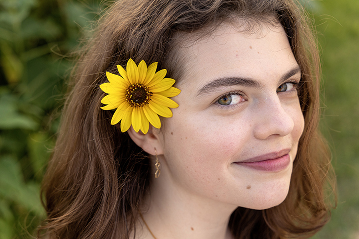 senior photo session, girl has sunflower in her hair at Commons Ford Ranch in Austin, Texas