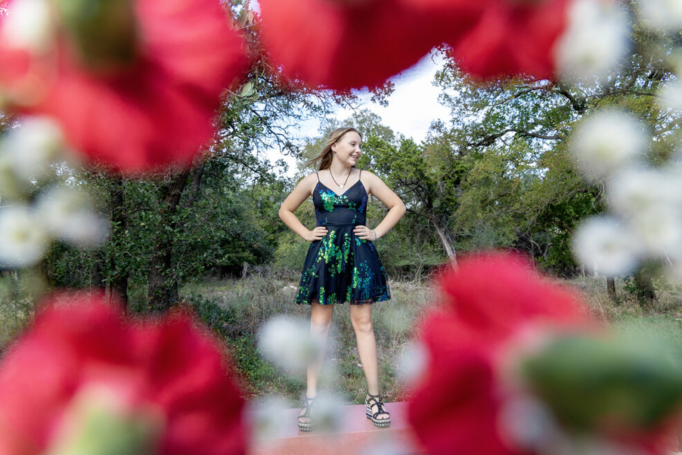 girl framed by red and white flowers