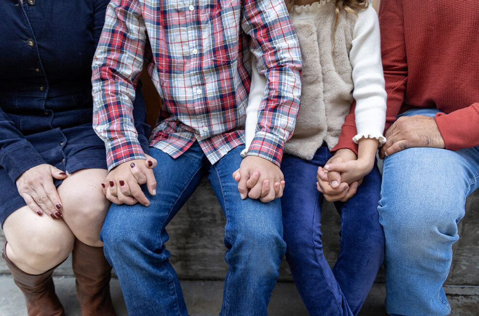 family of four all holding hands