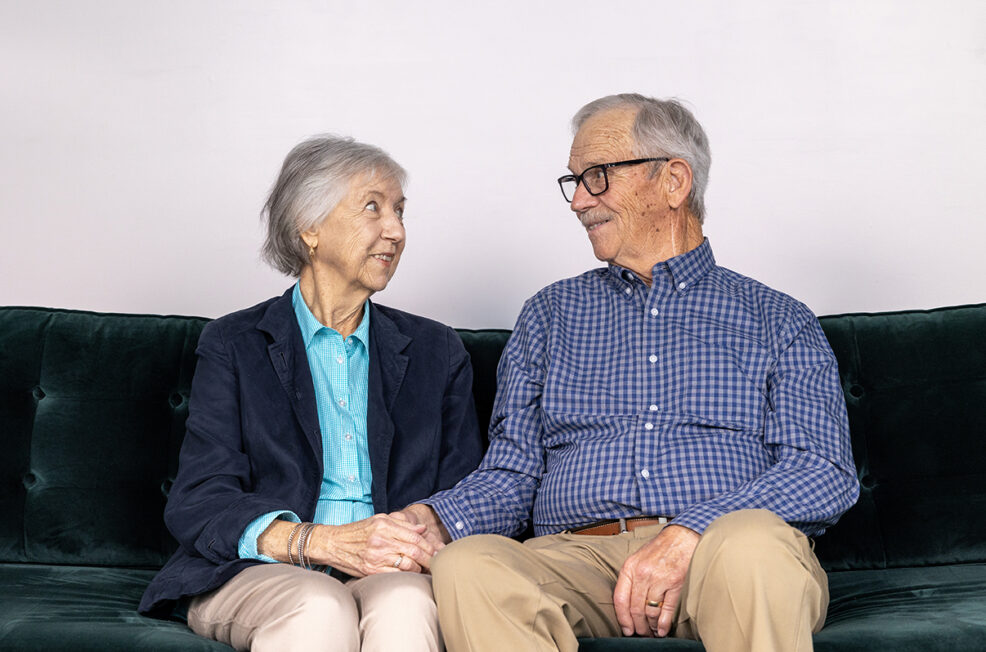 older couple holding hands on a green couch for a photo session in pflugerville, texas