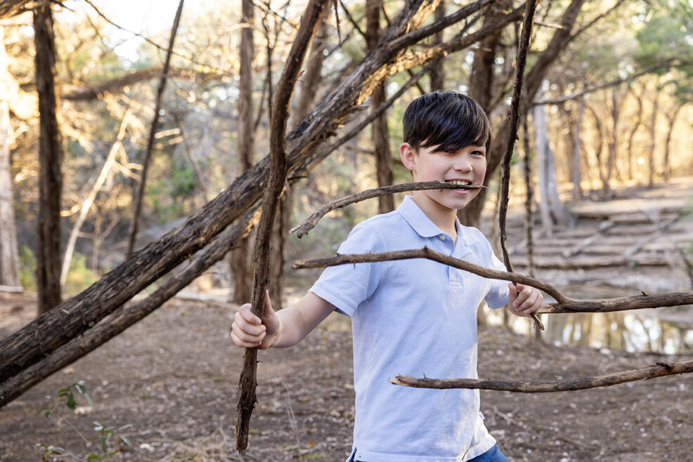 boy holding many sticks during photo session at the park