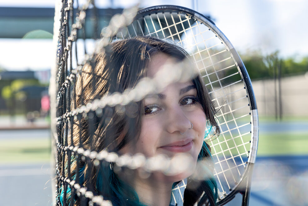 girls' face shown through a tennis court net austin texas high school photo session