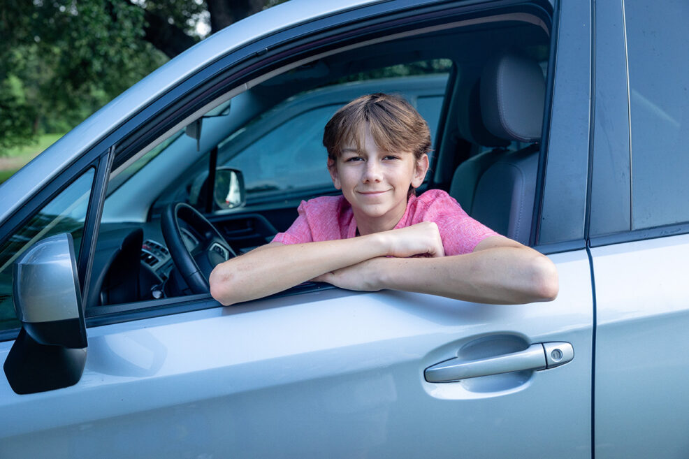 sixteen year old boy posing in family car for photo session in austin park