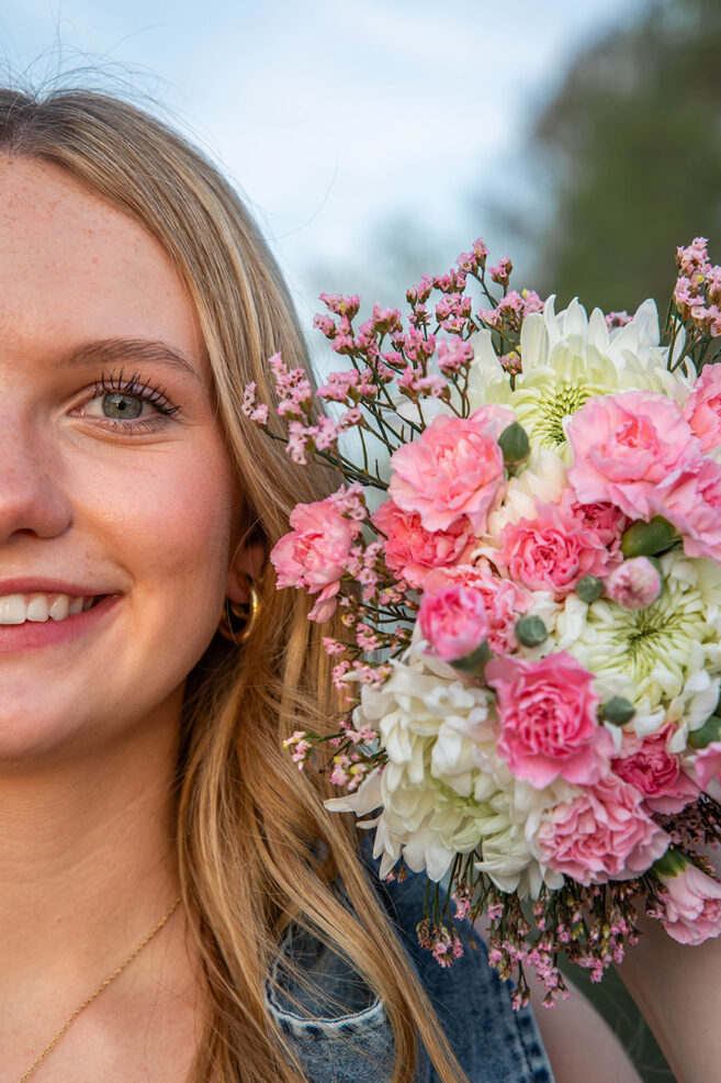 high school senior holding bouquet of flowers close to her face during photo session in austin