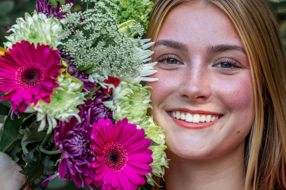 high school senior holding colorful bouquet of flowers for photo session