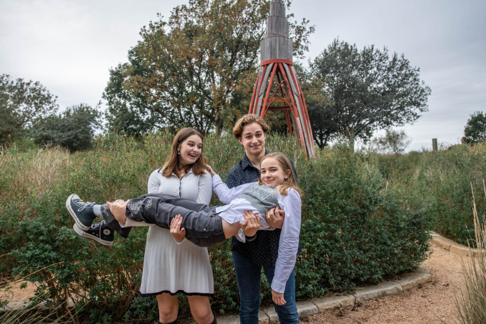 siblings holding their sister up during a family photo session