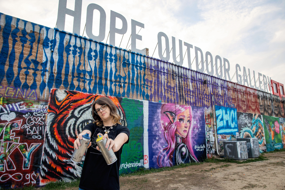 HOPE Outdoor Gallery wall with senior holding spray paint cans in front of it in Austin