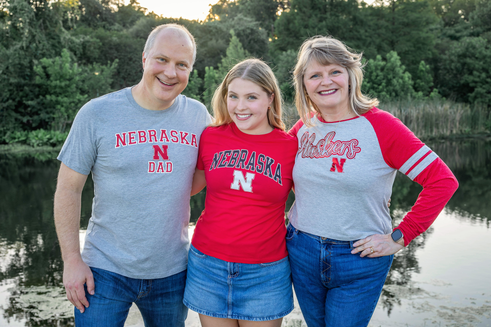 senior graduation photo session. the high school senior is wearing coordinating nebraska college shirts with parents
