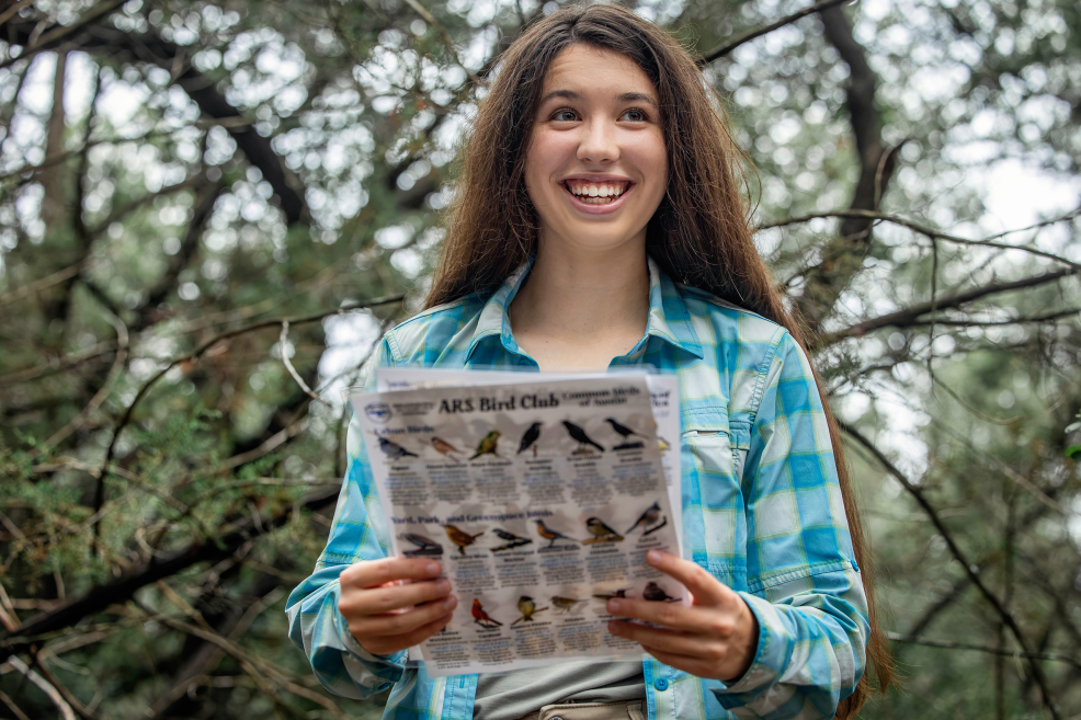 high school senior photo session holding up birding field guide pages